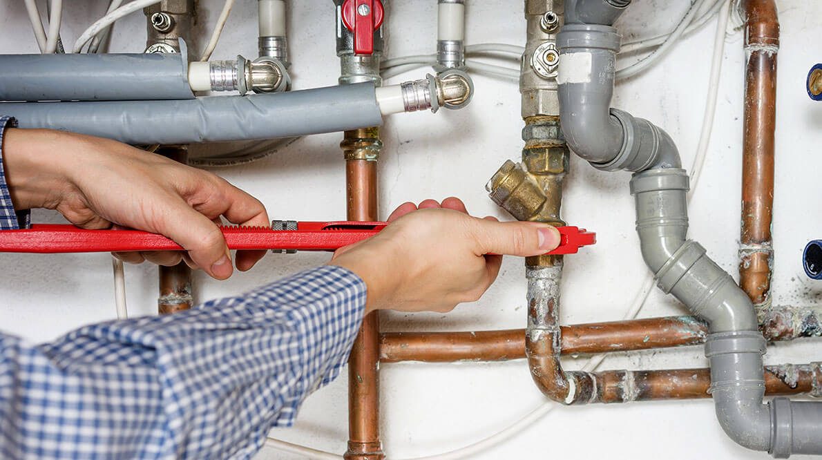 Technician tightening gas pipe fittings with a wrench